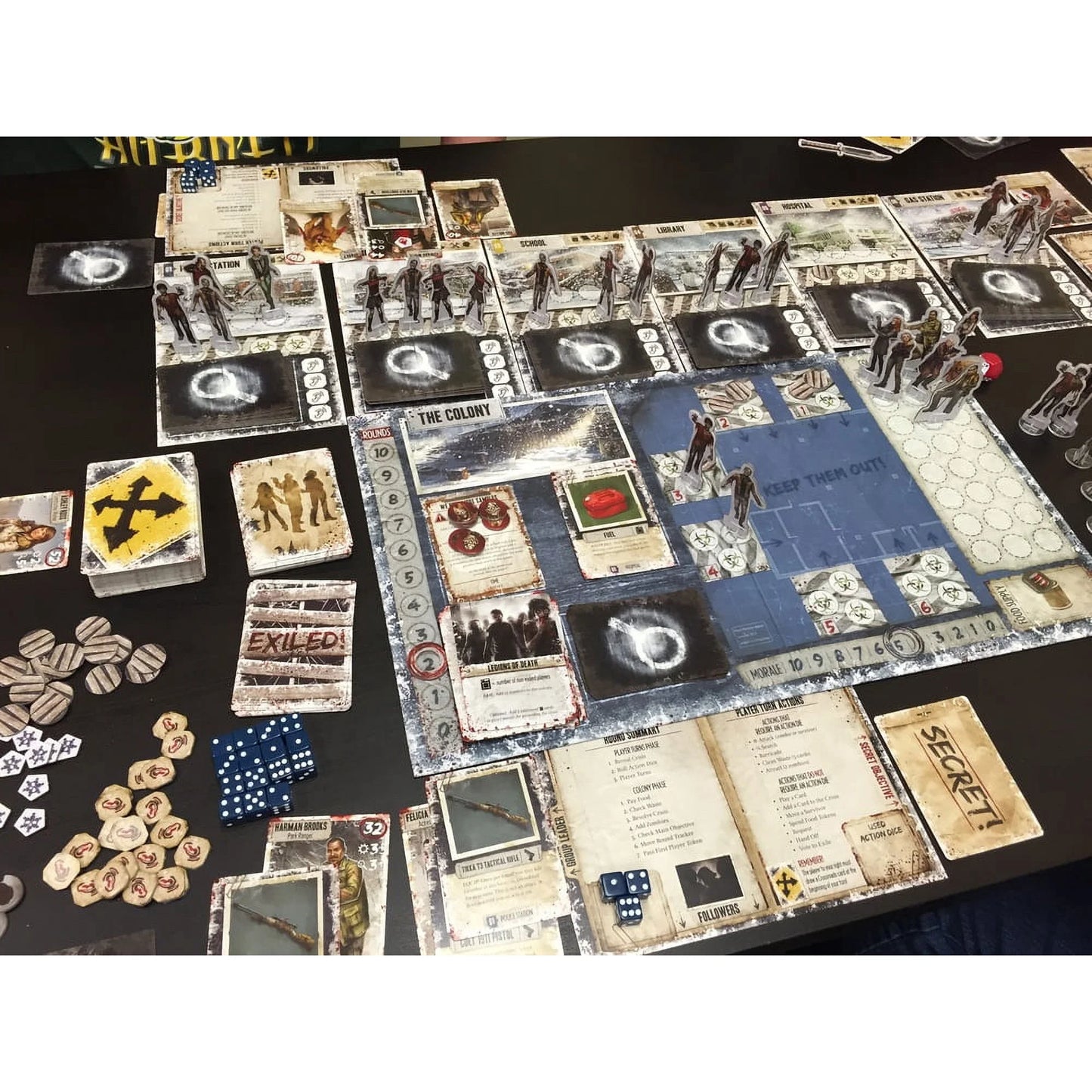Two players' game pieces and cards from Dead of Winter: A Crossroads Cooperative Strategy Board Game by Asmodee on a game board.