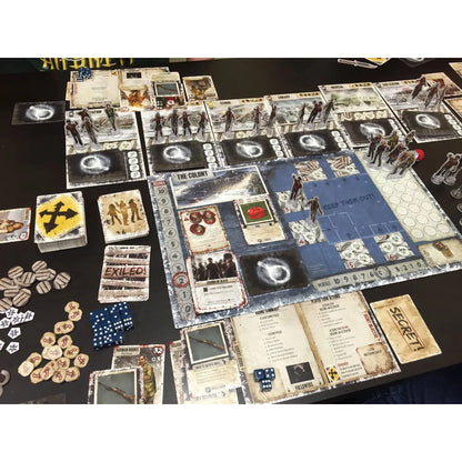 Two players' game pieces and cards from Dead of Winter: A Crossroads Cooperative Strategy Board Game by Asmodee on a game board.